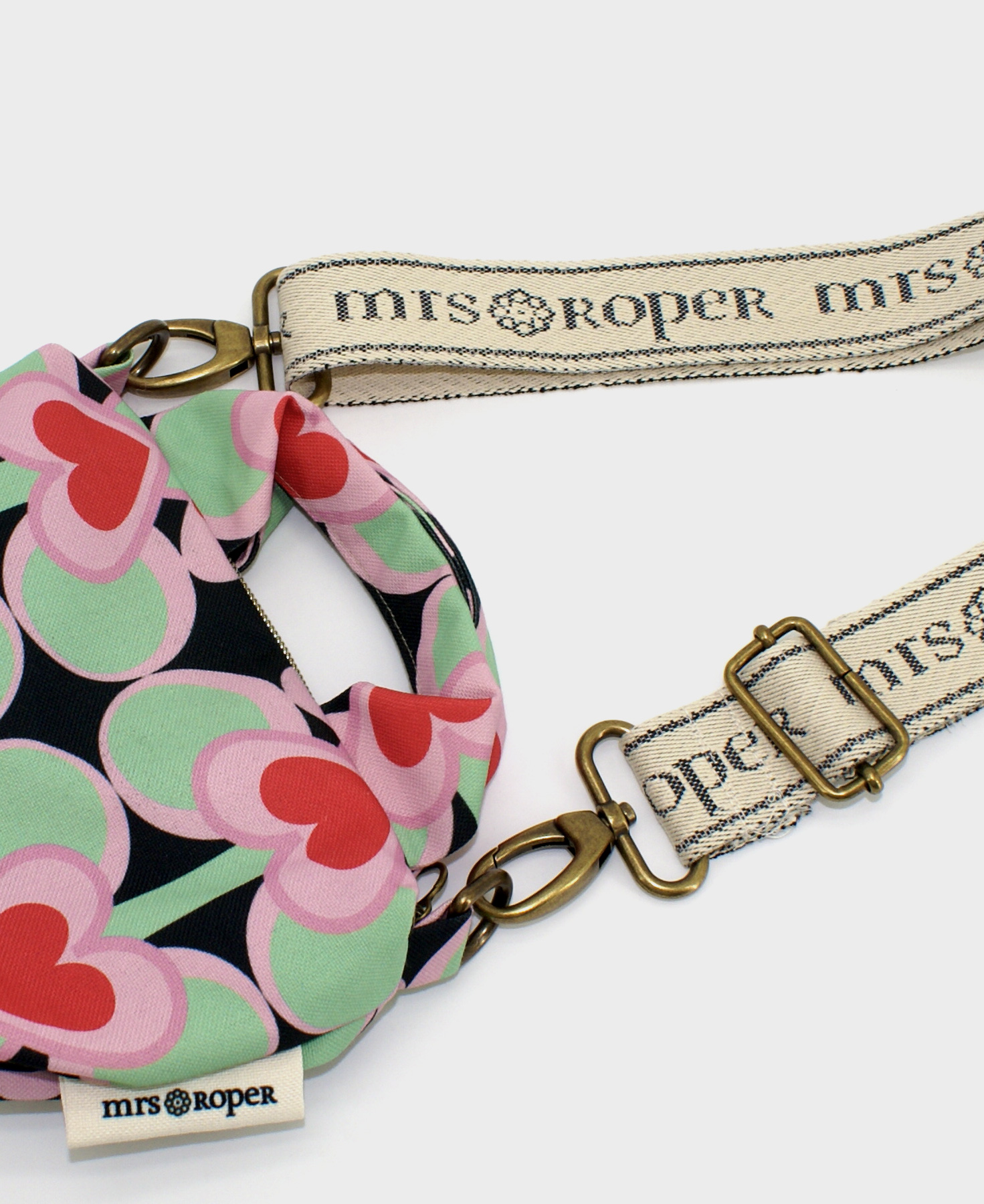 Bolso pequeño con asas, con estampado geométrico de corazones rojo sobre fondo negro, realizado en tejido reciclado RPET, de la marca Mrs. Roper.