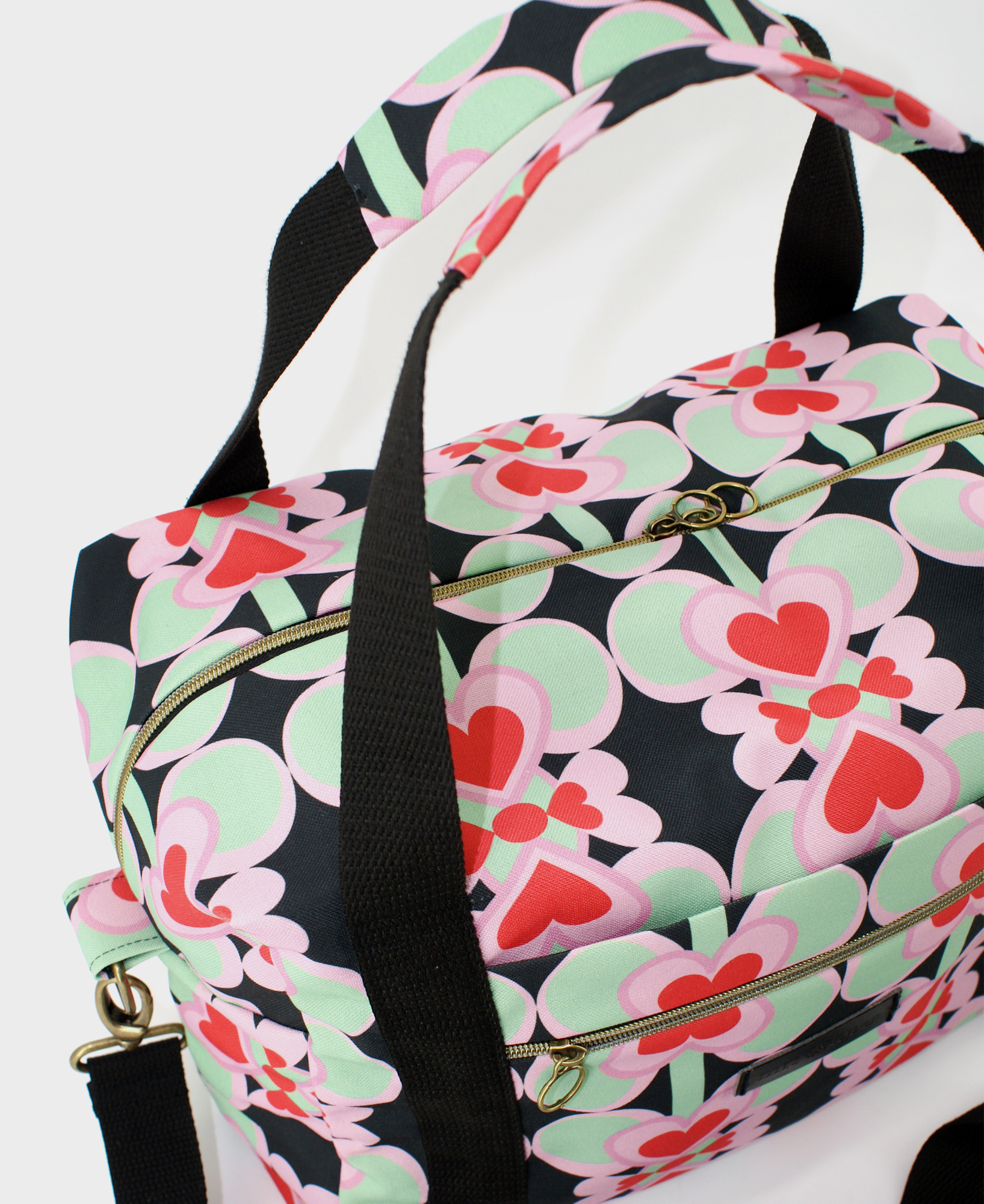 Bolsa de viaje hecha de tejido reciclado RPET con estampado de corazones en rojo y rosa sobre fondo negro de la marca Mrs. Roper.