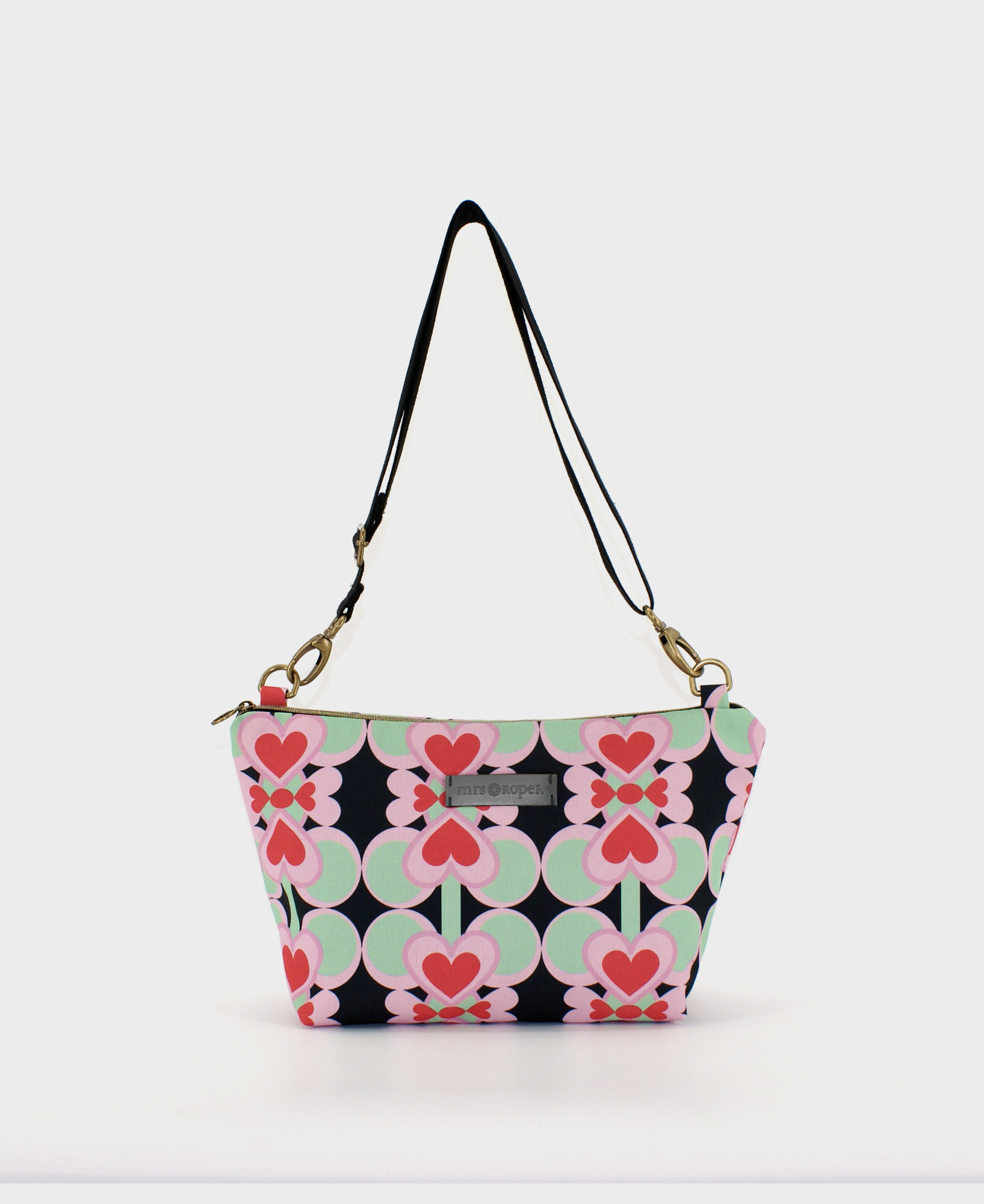 Bandolera mediana de mujer, realizada en tejido reciclado de botellas de plástico RPET, con estampado geométrico de corazones rojos sobre fondo negro, de la marca Mrs. Roper.