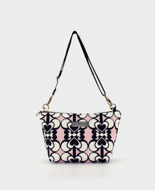 Bandolera mediana de mujer, realizada en tejido reciclado de botellas de plástico RPET, con estampado geométrico de corazones en negro, rosa y blanco, de la marca Mrs. Roper.