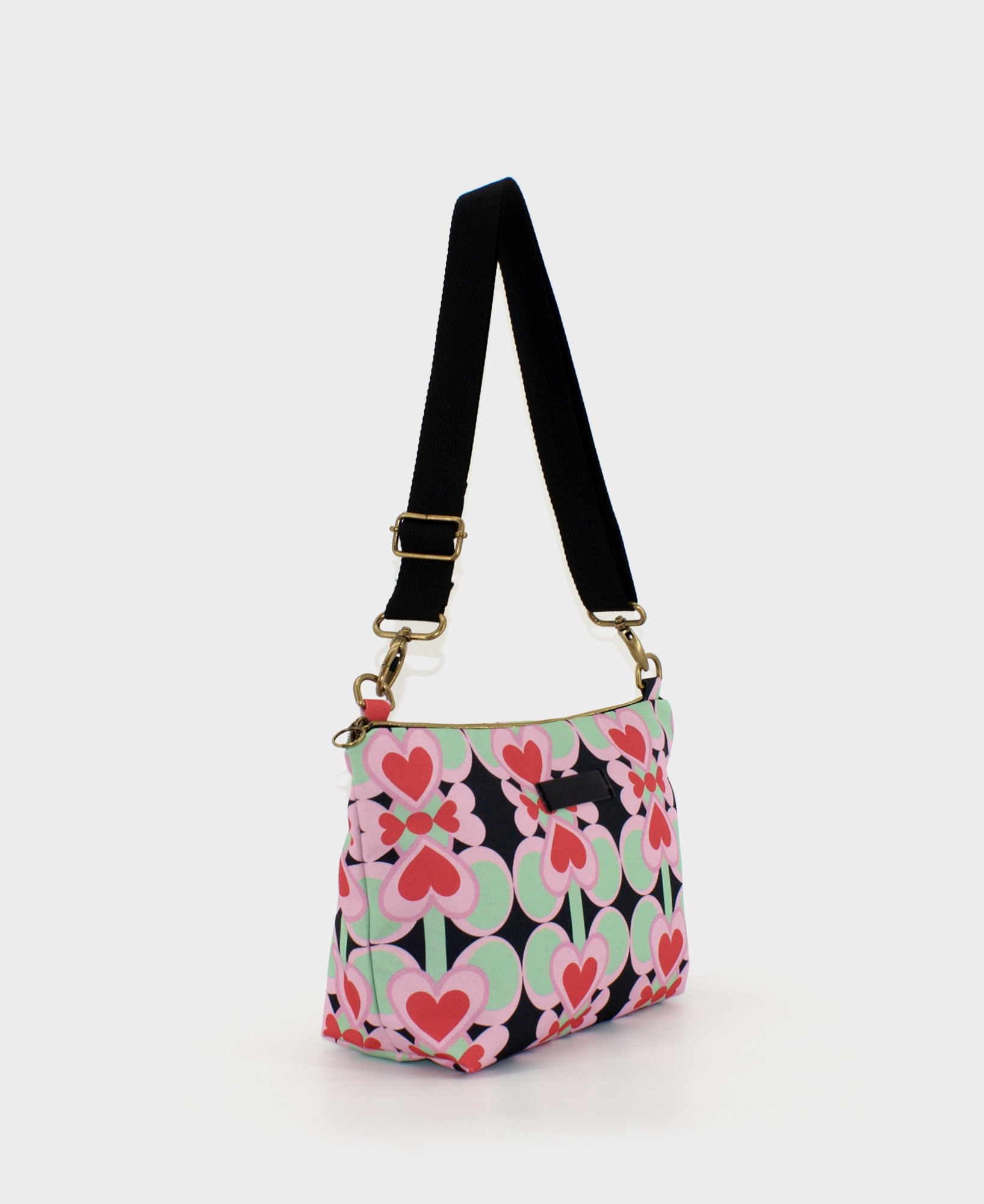 Bandolera mediana de mujer, realizada en tejido reciclado de botellas de plástico RPET, con estampado geométrico de corazones en rojos sobre fondo negro, de la marca Mrs. Roper.