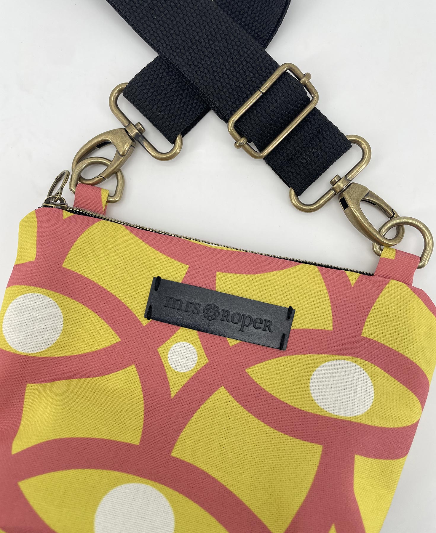 Bandolera pequeña de mujer realizada en tejido reciclado RPET con estampado geométrico amarillo, blanco y salmón, de la marca Mrs. Roper.