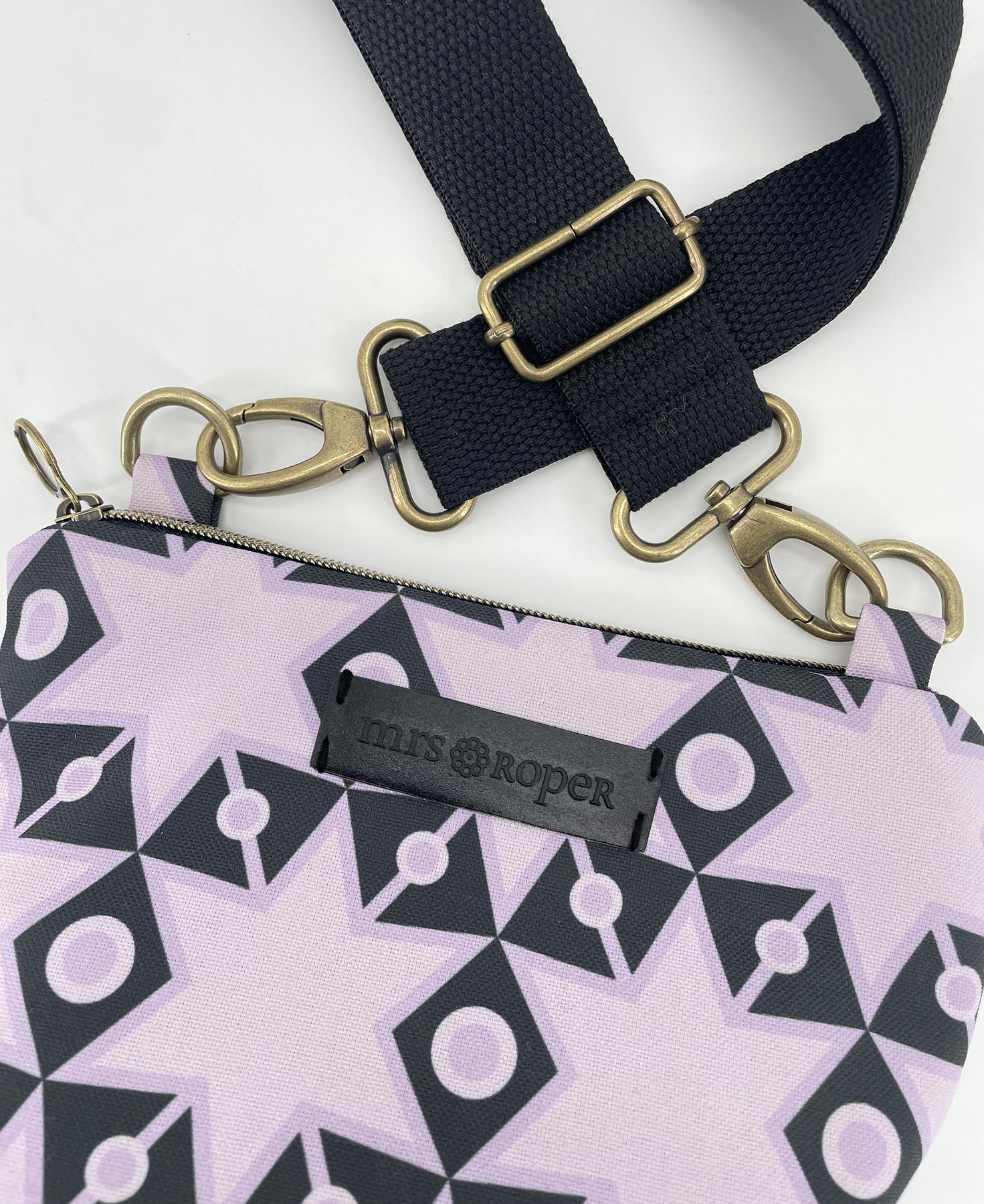 Bandolera pequeña de mujer realizada en tejido reciclado RPET con estampado geométrico de estrellas en lila y negro, de la marca Mrs. Roper.