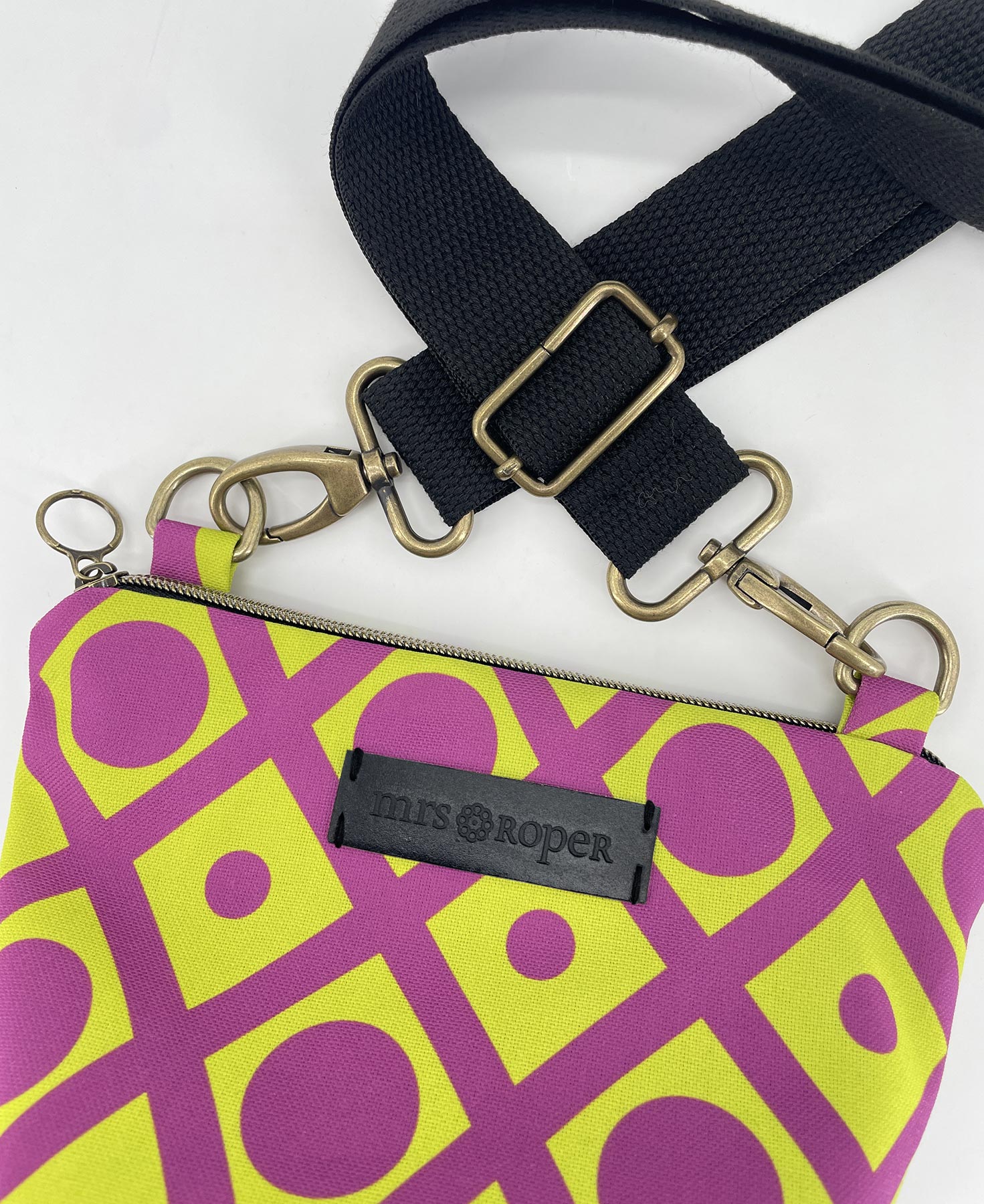 Bandolera pequeña de mujer realizada en tejido reciclado RPET con estampado geométrico lima y morado, de la marca Mrs. Roper.