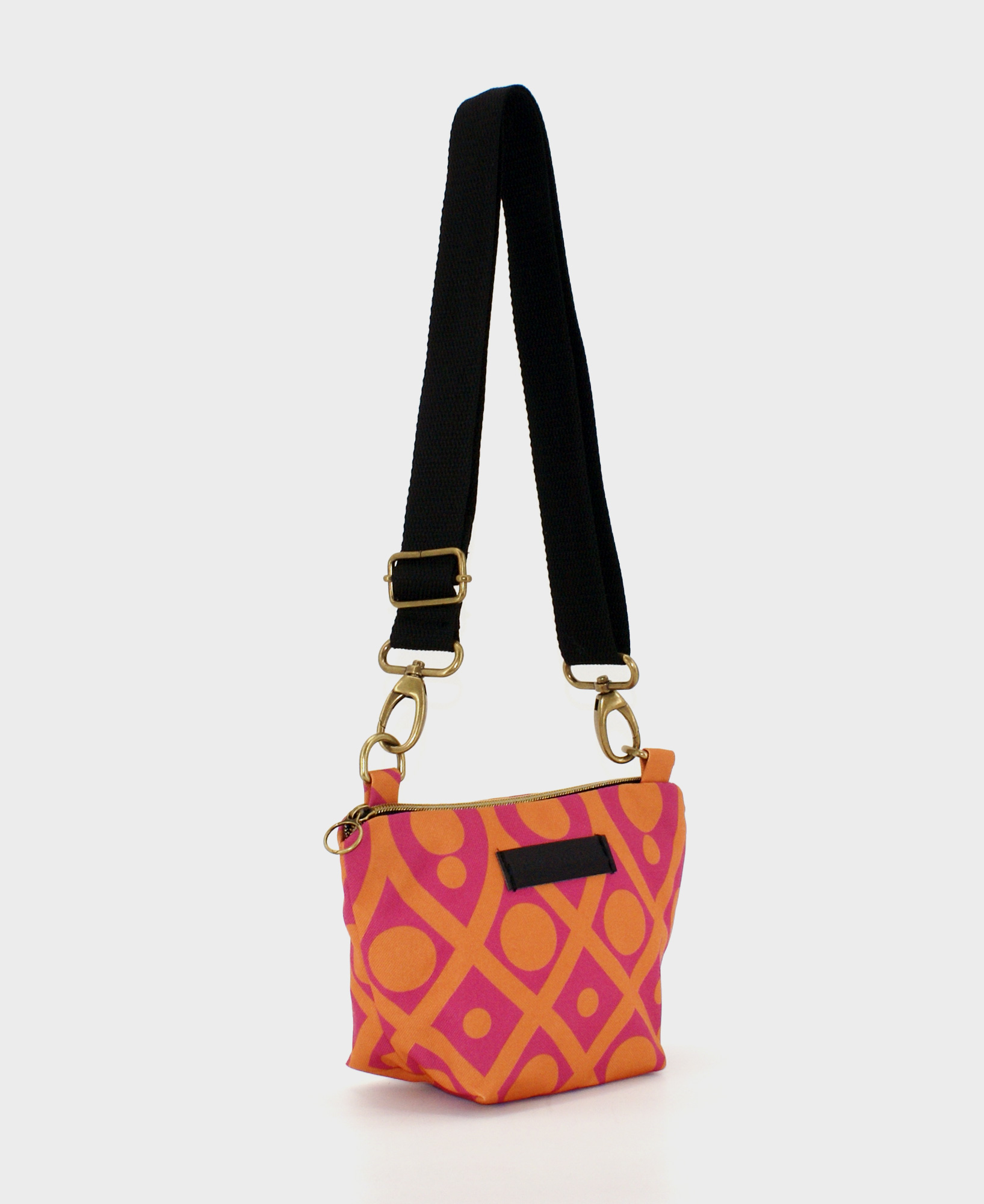 Bandolera pequeña de mujer, realizada en tejido reciclado RPET con estampado geométrico en fucsia y naranja, de la marca Mrs. Roper.