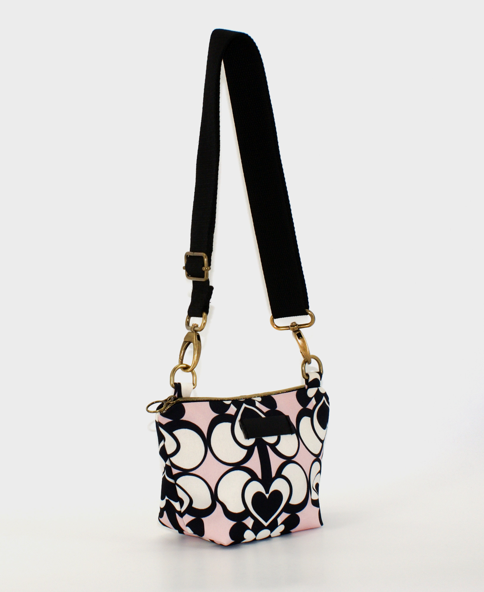 Bandolera pequeña de mujer, realizada en tejido reciclado RPET con estampado geométrico de corazones en blanco, negro y rosa de la marca Mrs. Roper.