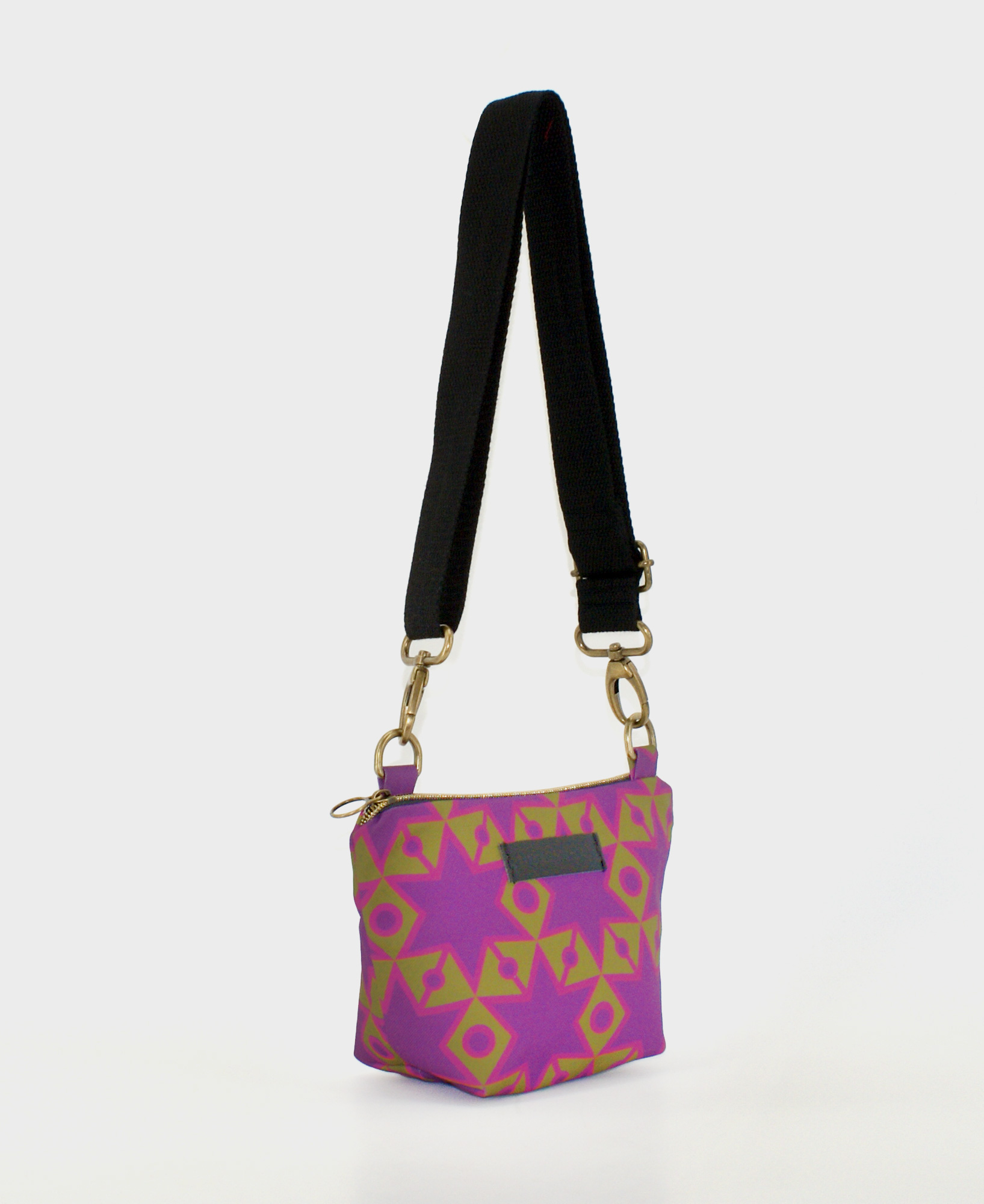 Bandolera pequeña de mujer, realizada en tejido reciclado RPET con estampado geométrico de estrellas en morado y verde, de la marca Mrs. Roper.