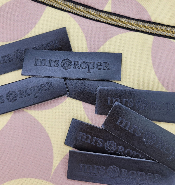 Etiquetas de la marca Mrs. Roper en cuero reciclado de color negro.