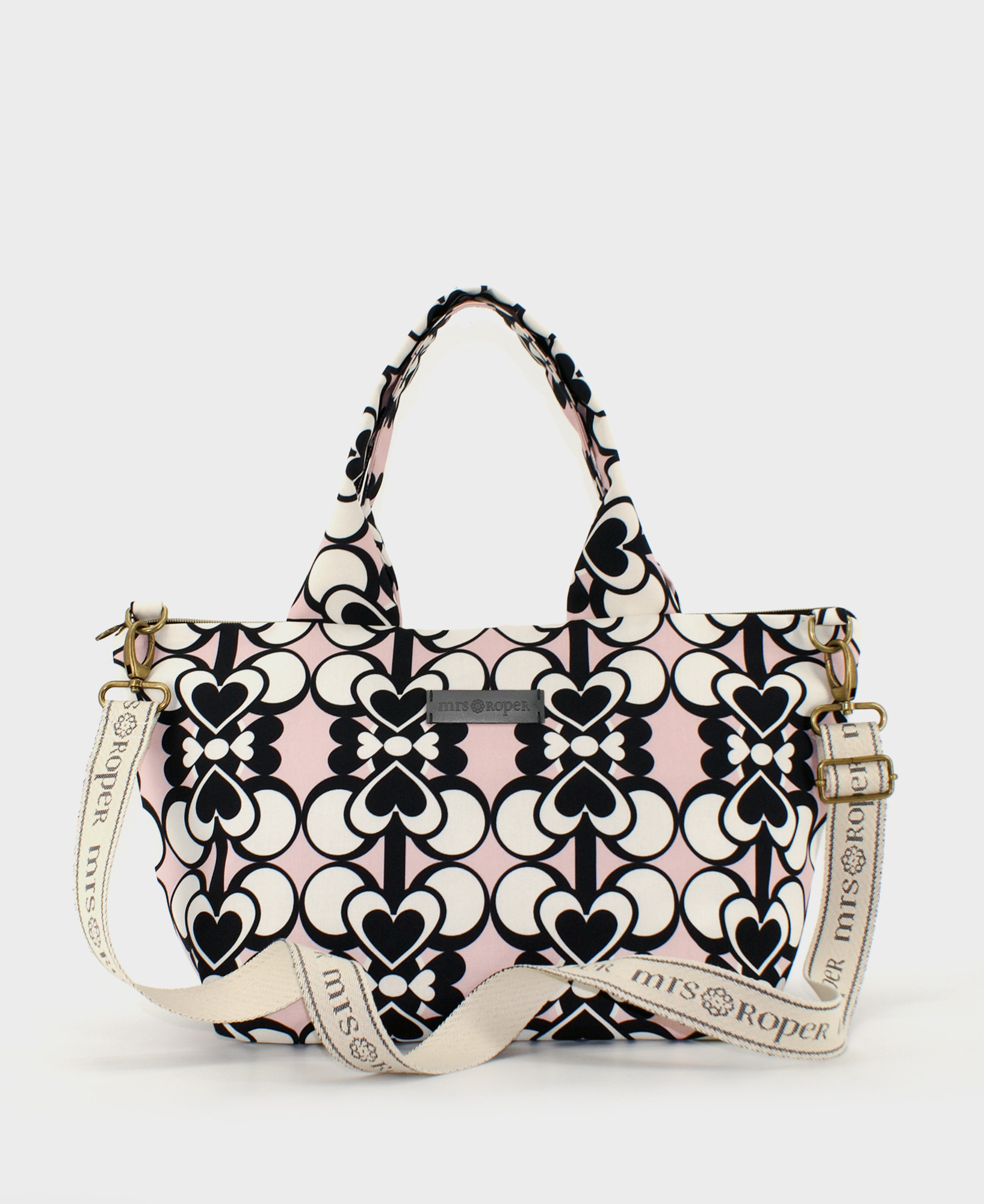 Bolso de hombro de mujer, realizado en tejido reciclado RPET con estampado de corazones blanco y negro sobre fondo rosa, de la marca Mrs. Roper.