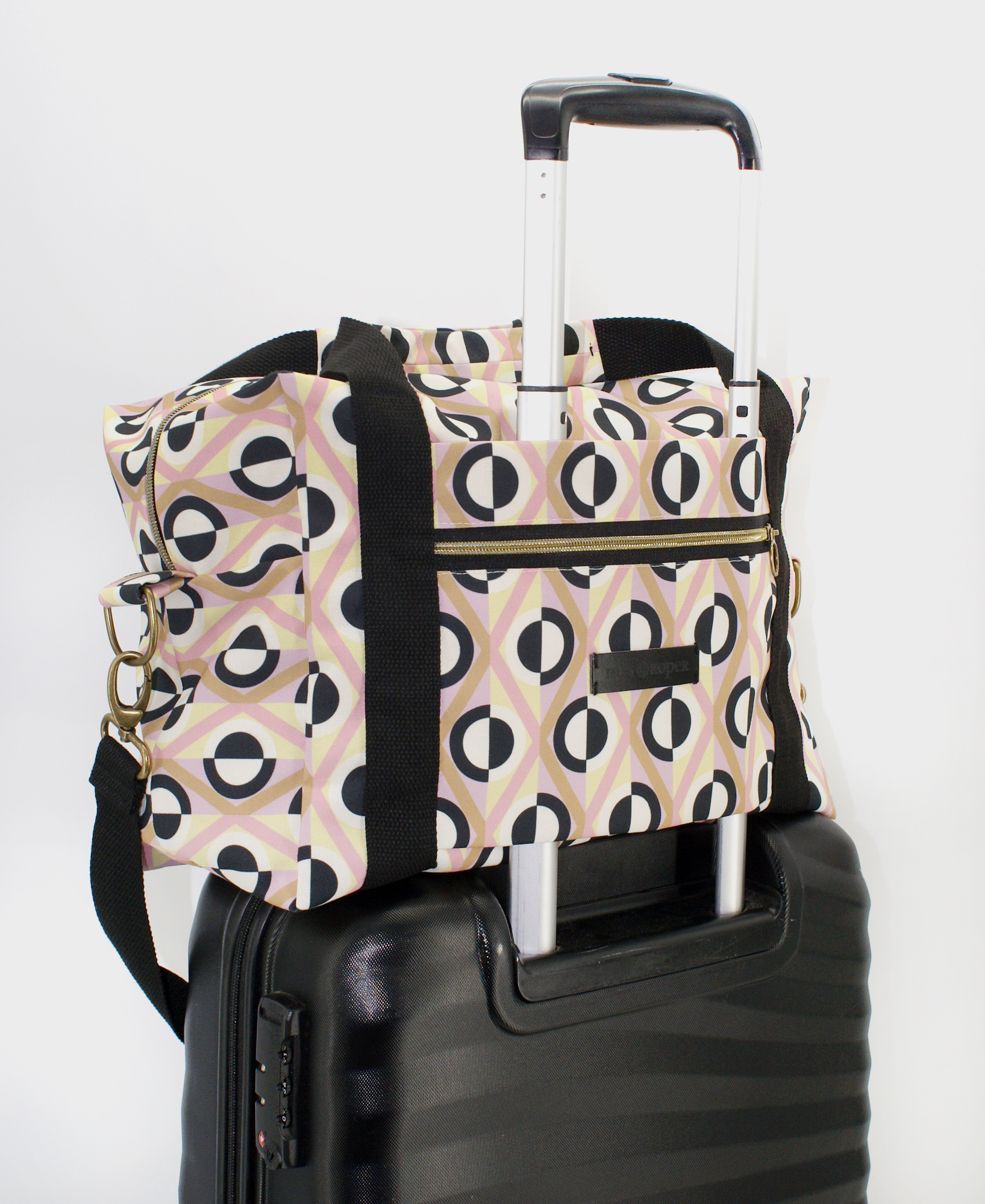 Bolsa de viaje con estampado geométrico de rombos en rosa, beige, negro y blanco, hecha en tejido reciclado RPET de la marca mrs Roper.